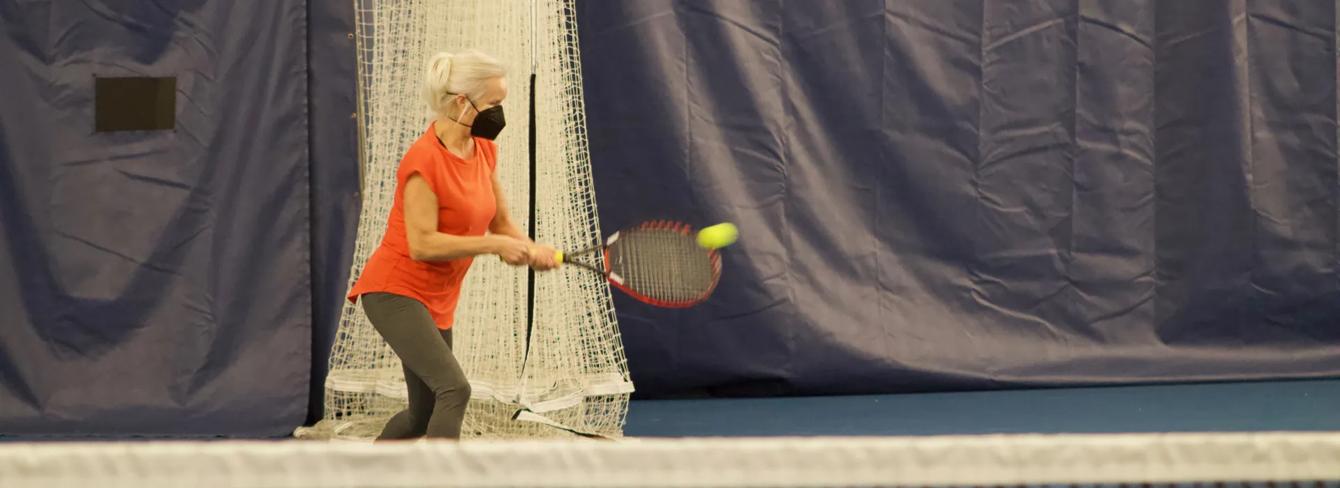 A woman playing tennis runs to hit a ball back across the court.