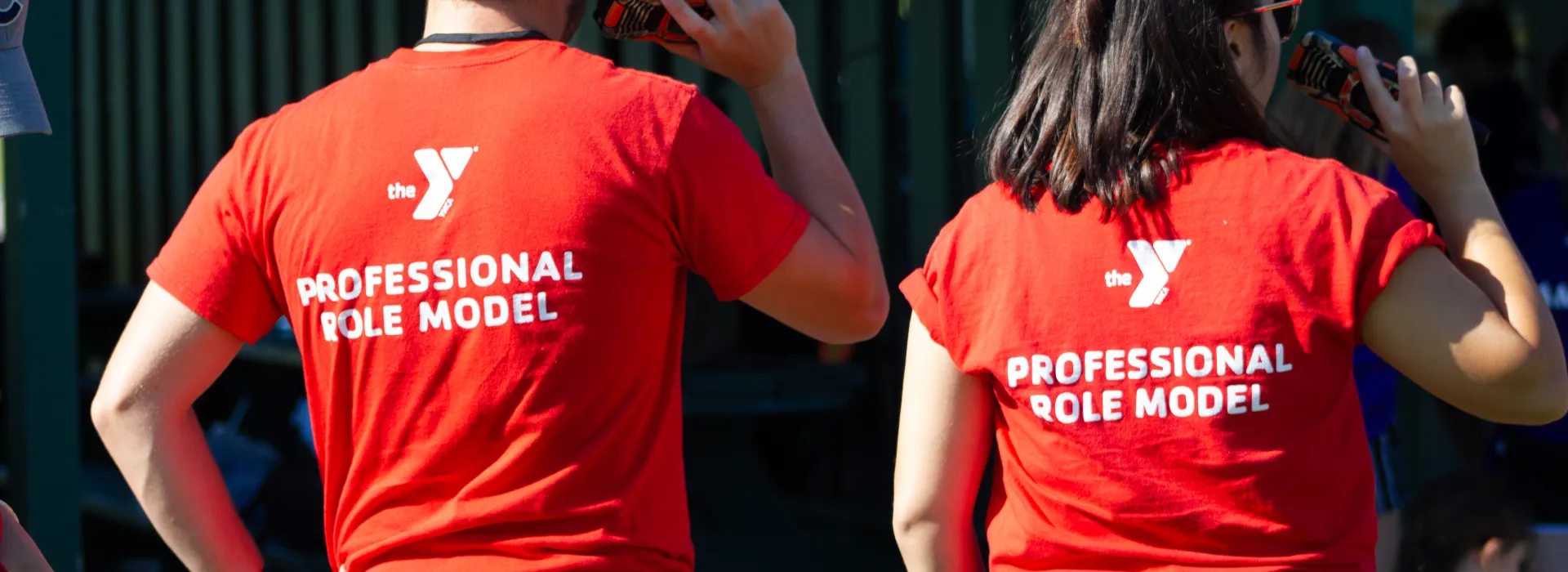 Two YMCA team members facing away show off their Professional Role Model team shirts.