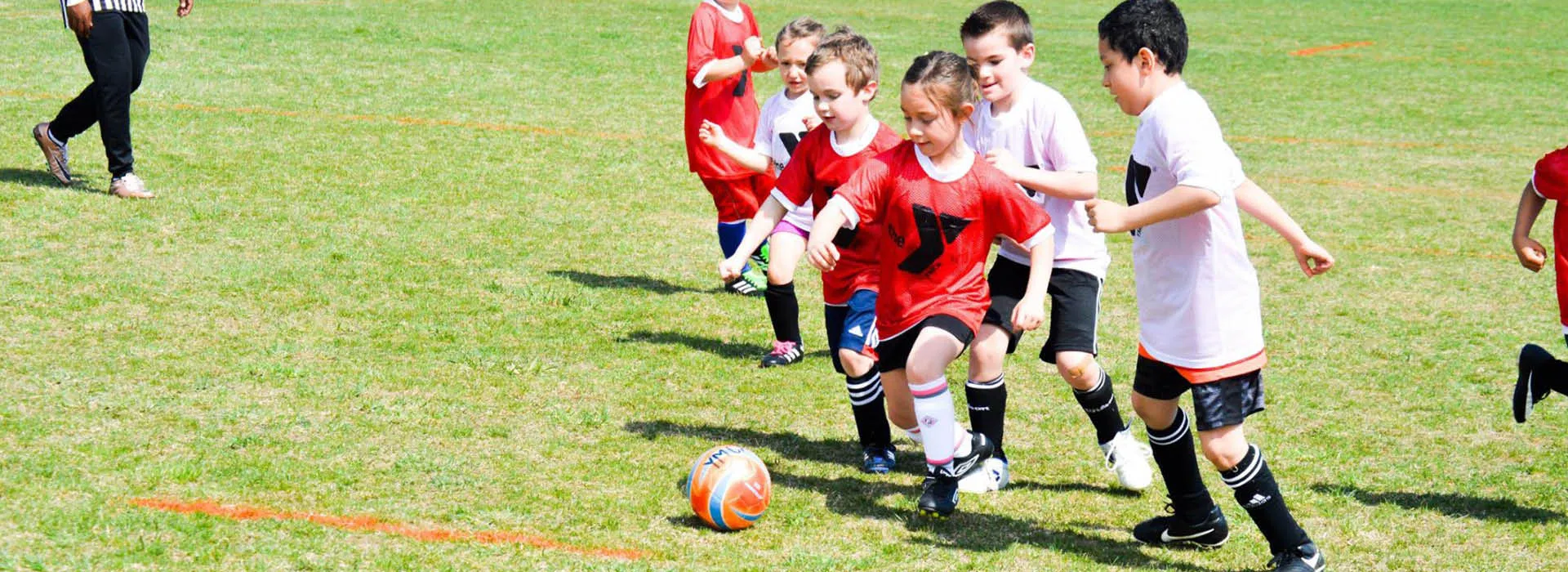 Two opposing young soccer teams rush to kick the ball.