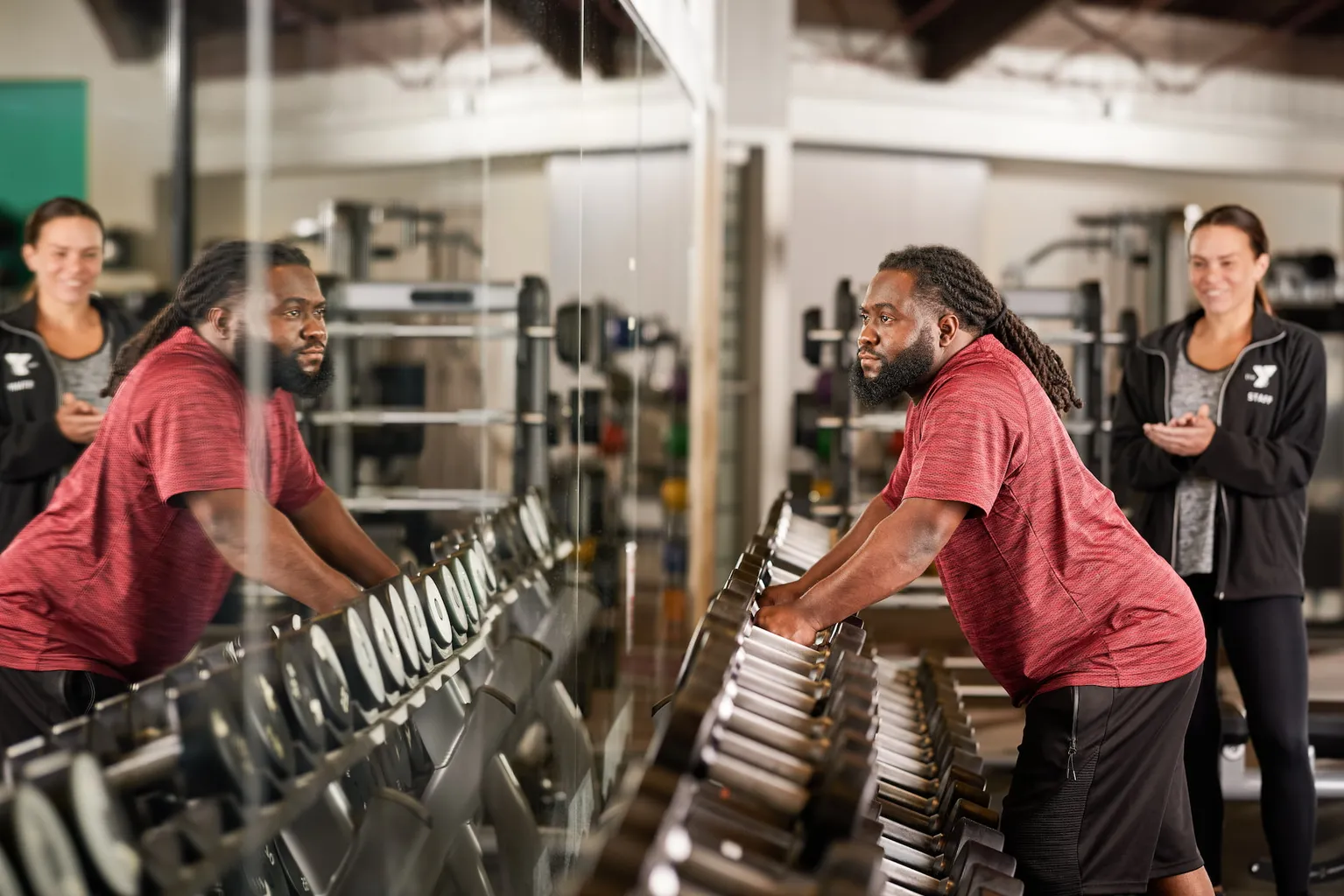 YMCA member looks into the mirror as they pick up a new set of weights.