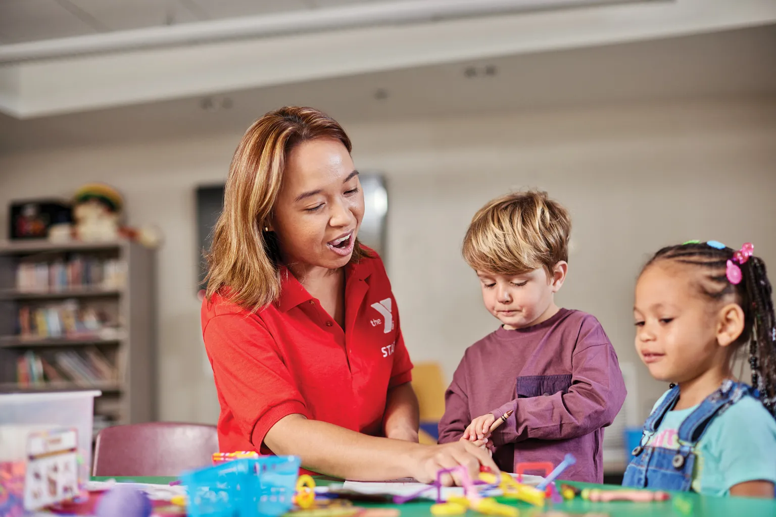 Y Team member sits at a table, working through puzzles with young child.