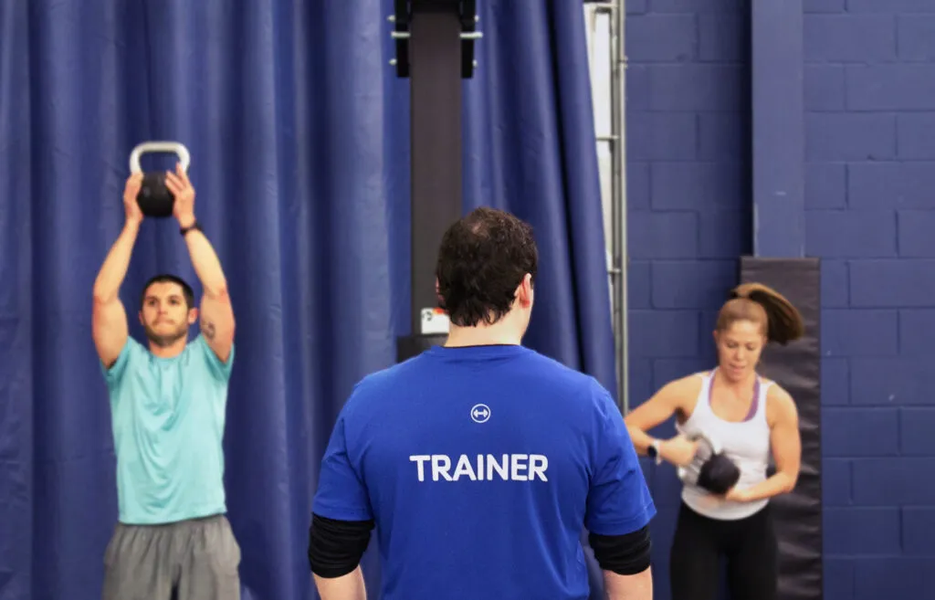 Trainer stands in front of class as they perform reps.