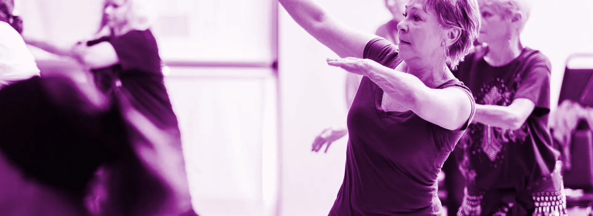 In a purple room, a woman performs a lively dance, embodying the spirit of the Enhance Fitness initiative