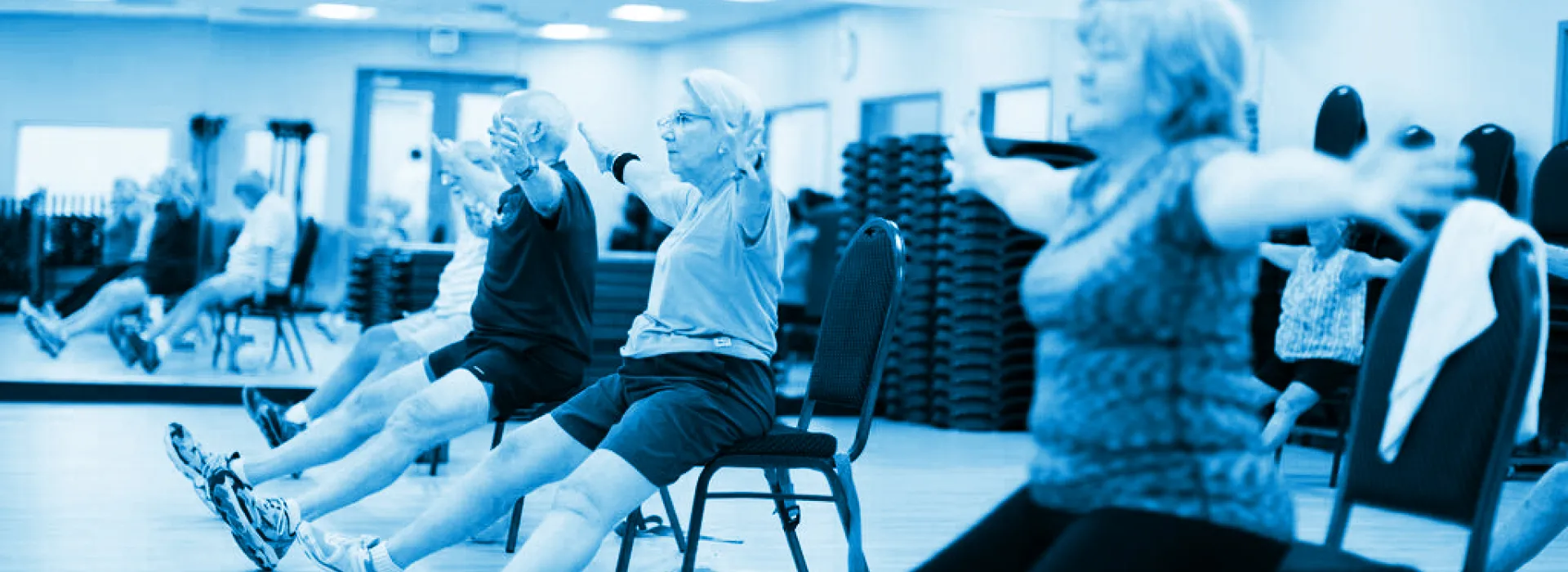 Participants engaged in Ageless Grace exercises for Parkinson's in a gym, showcasing camaraderie and physical activity.