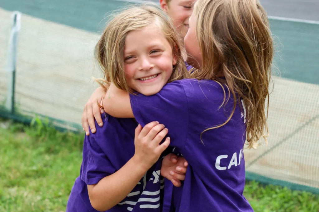 Two campers smiling and hugging
