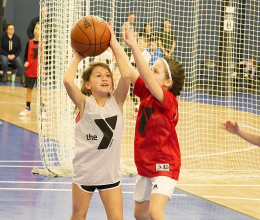 girl shooting a basketball while being defended