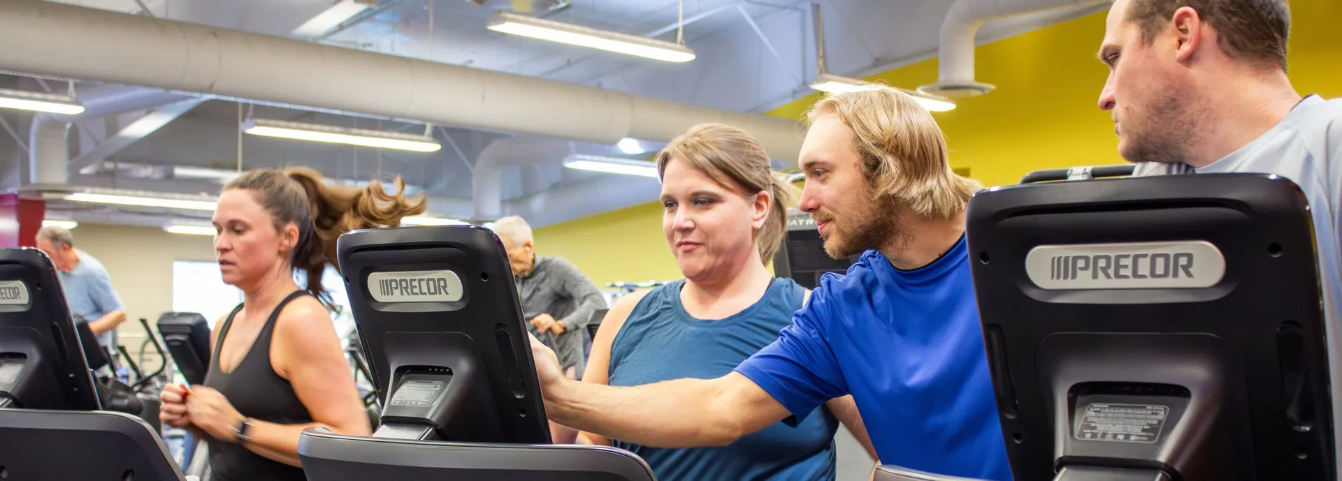 Trainer helps gym member use treadmill