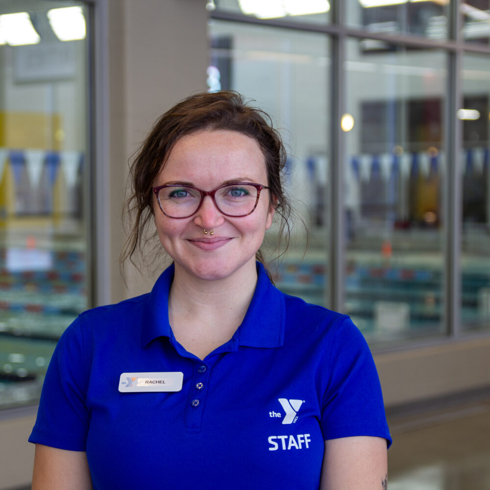 Portrait of young woman with dark hair and glasses, smiling at camera.
