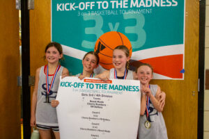 Team of four girls posing with their winning medals from the 3v3 basketball tournament.