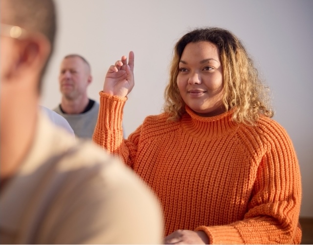 Woman with orange sweater participating in group lecture